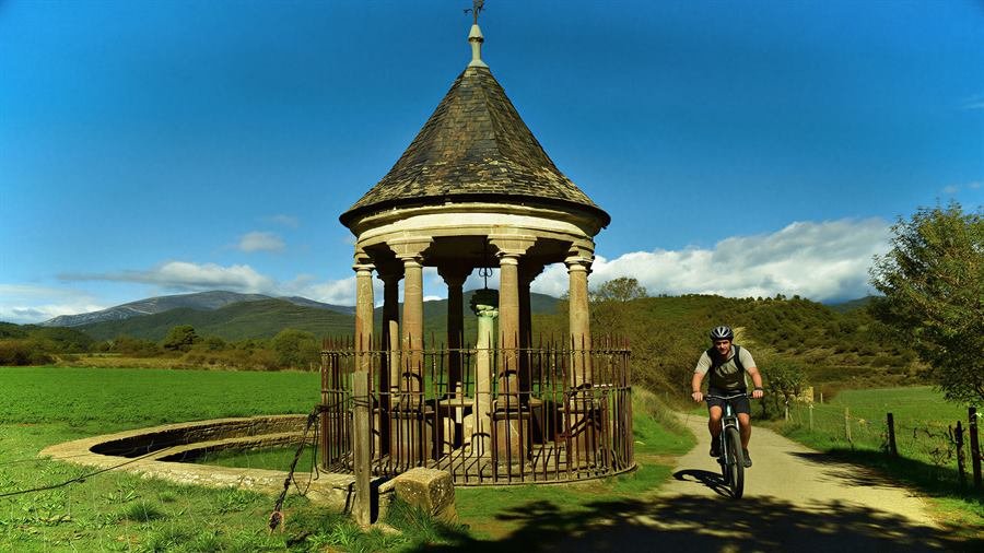 La Cruz Cubierta, pequeño templete circular, con un ciclista en el camino