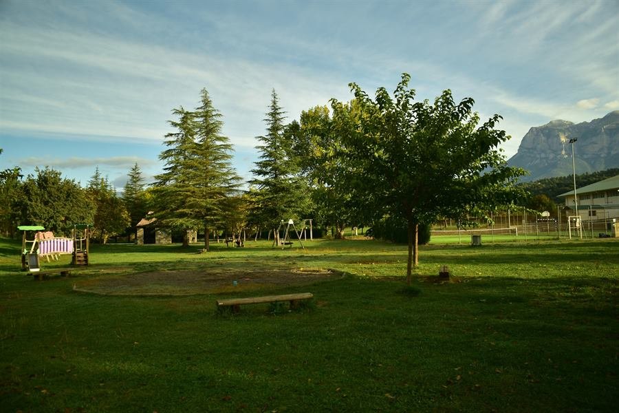 Parque Nabateros, con juegos infantiles, árboles y la Peña Montañesa al fondo