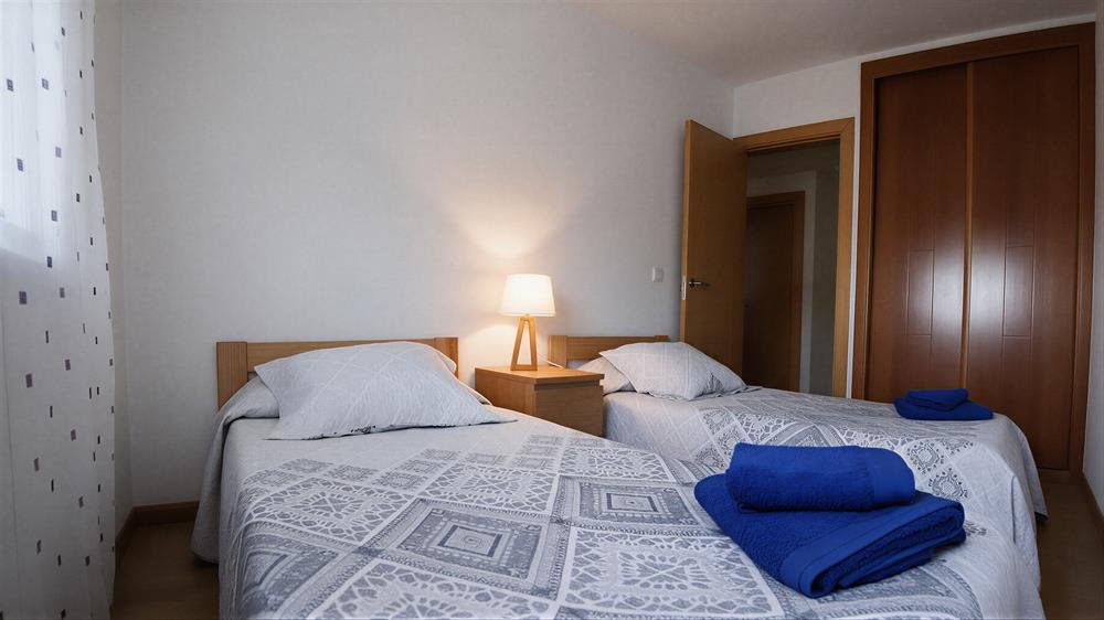 Dormitorio de dos camas individuales: vista general de las camas, mesilla y ventana