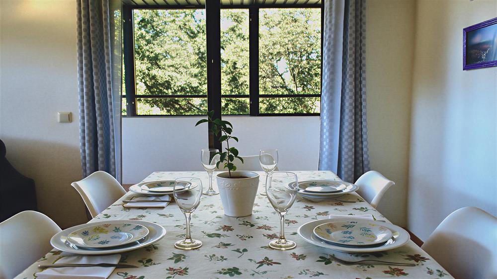Mesa del comedor puesta para cuatro, con ventana a los árboles